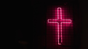 A neon cross hanging on a wall.