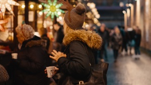A woman standing in line surrounded by people and Christmas lights.