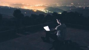 A person sitting at night looking at computer screen.