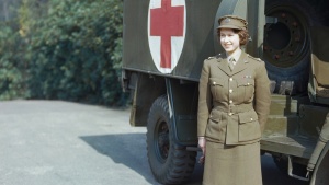 A photo of a young Queen Elizabeth standing in front of an army ambulance,