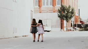 A photo of two young girls with arm around each other.