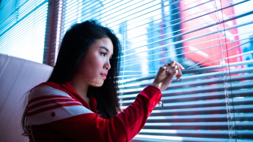 A young woman looking out a window.