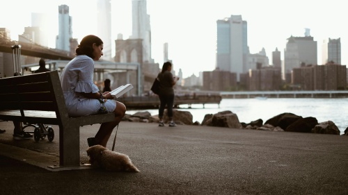 A woman sitting on a park bench reading.