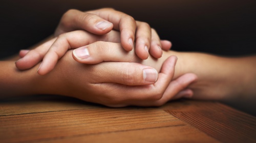 Two people's hands touching and showing comfort.